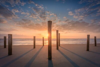 Zonsondergang door houten palen op het strand