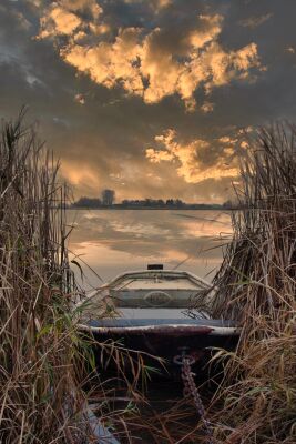 Zonsondergang aan het water met een bootje in het riet