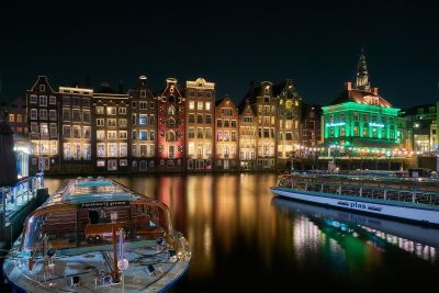 Het Damrak met rondvaartboten te Amsterdam in de avond