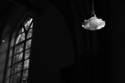 Zonlicht schijnt op glazen lampenkap in donkere kerk