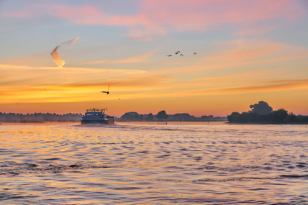 Vrachtschip op de Lek tijdens zonsopkomst