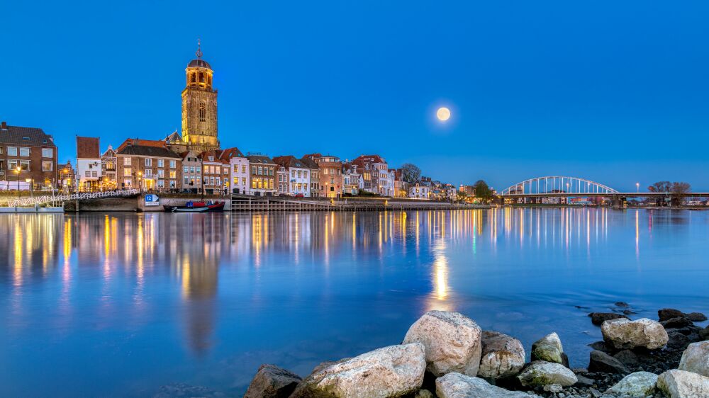 De skyline van Deventer in de avond bij volle maan