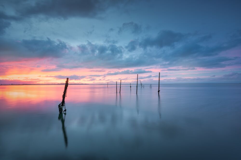 Rustige zonsondergang aan de kust met spiegelgladde wateren