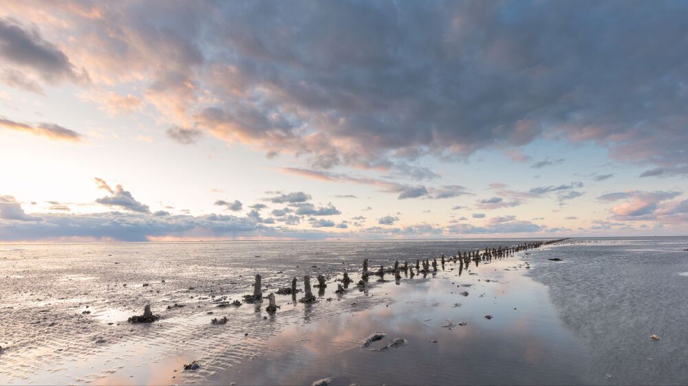 Wolken boven de paaltjes op het Wad