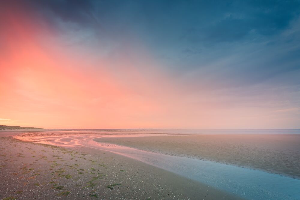 A tranquil sunrise on the coast with soft colours of pink and blue