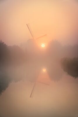 Serene Dutch landscape with a windmill in the morning mist