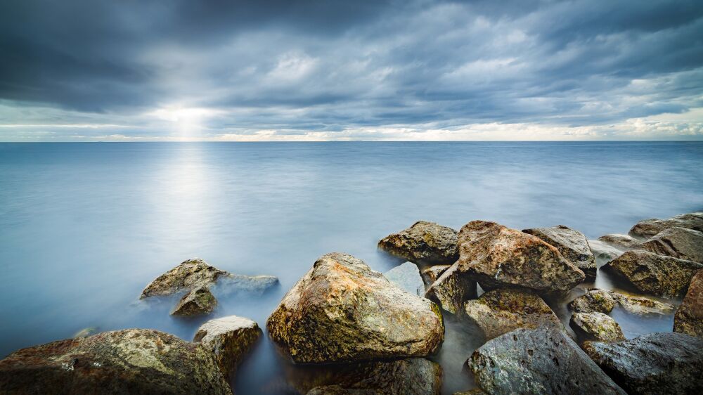 Rays of light through the dark clouds above the water surface of the IJsselmeer