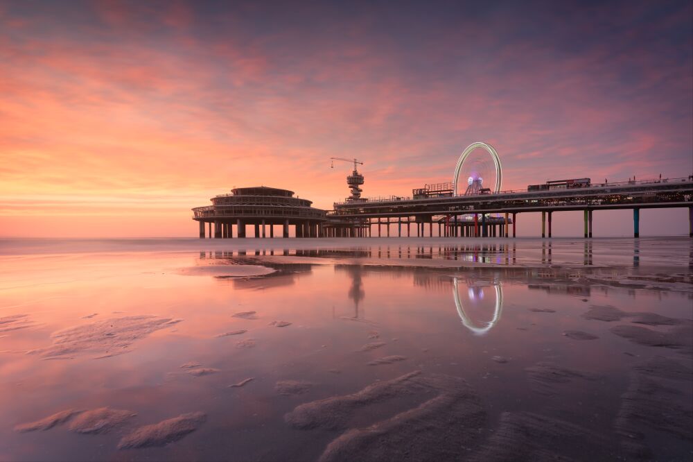 Prachtige zonsondergang bij de pier van Scheveningen met reflecties in het water