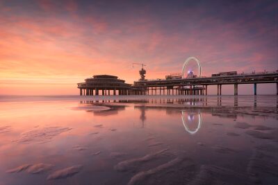 Beautiful sunset at the Scheveningen Pier with reflections in the water