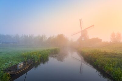 Serene Dutch landscape with a windmill in the morning mist