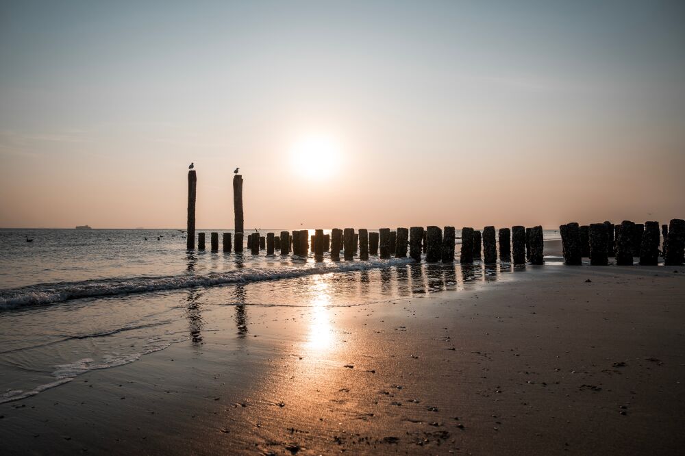 Sonnenuntergang am Strand mit Wellenbrechern