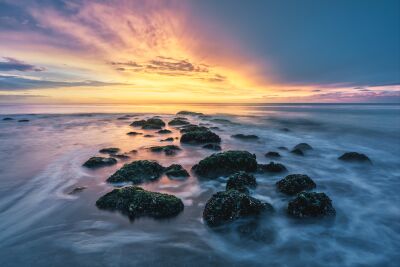 Spectacular sunset at sea with rocks in the water