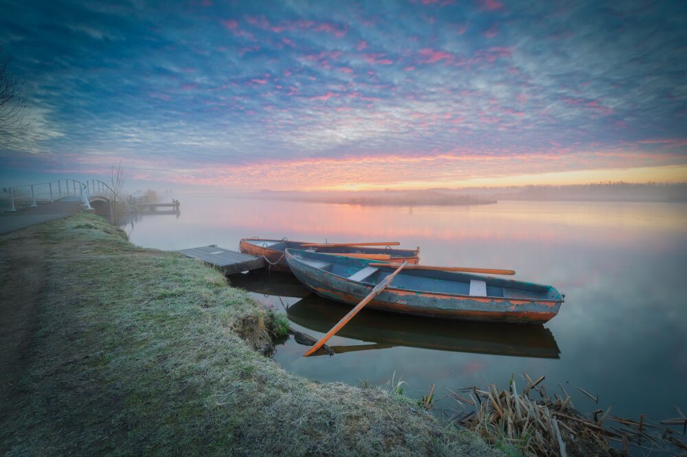 Magical sunrise at a tranquil river landscape with rustic boats