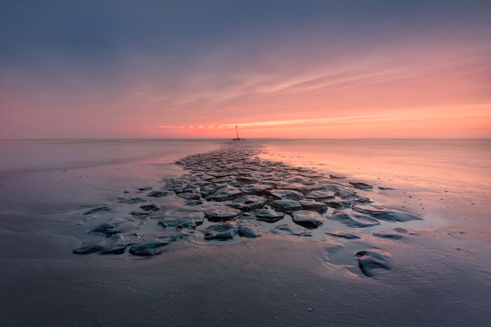 Rustgevende zonsondergang boven een rotsachtig pad naar de horizon