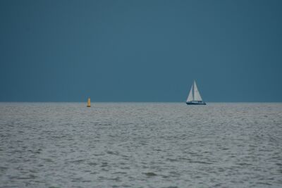 Gele boei en zeilboot tegen een dreigende lucht