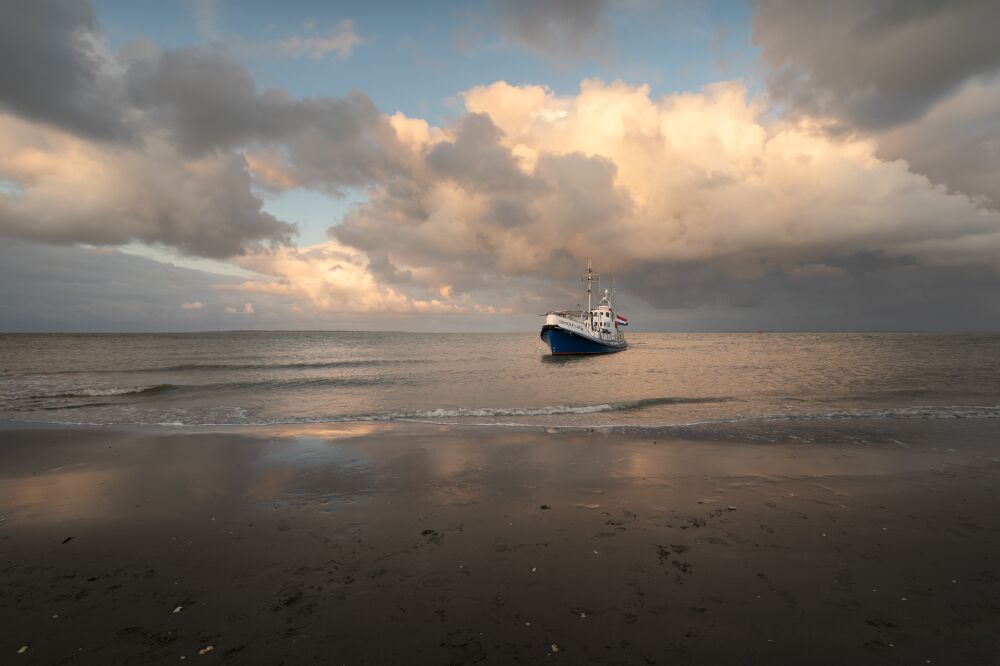 Boot aan het strand onder dreigende lucht