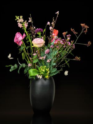 Stilleven roze bloemen in zwarte vaas