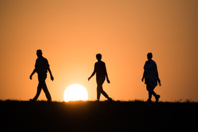 wandelaars op de dijk tijdens zonsondergang